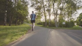 Beautiful fitness athlete man jogging outdoors in the park with sunlight. Video footage in Full HD video slow motion 50 fps (1920x1080)
