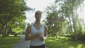 Beautiful fitness athlete woman jogging outdoors in the park with sunlight. Video footage in Full HD video slow motion 50fps (1920x1080)
