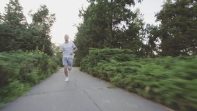 Beautiful fitness athlete man jogging outdoors in the park with sunlight. Video footage in Full HD video slow motion 50 fps (1920x1080)