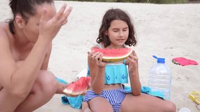 children kids teenagers on the beach resting laughing and eating watermelon slow motion video. girl teenager resting on the beach in summer. little girl