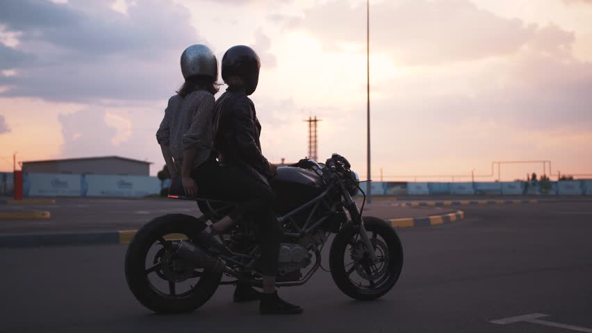 Young couple in helmets on motorcycle on the road with beautiful sunset sky background | Shutterstock HD Video #1014238736