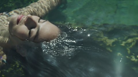 Close up high angle view of woman floating in natural pool / Meadow, Utah, United States