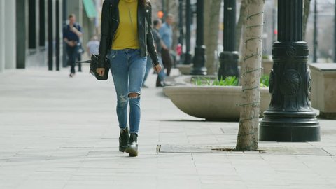 Woman walking on city sidewalk and looking around / Salt Lake City, Utah, United States