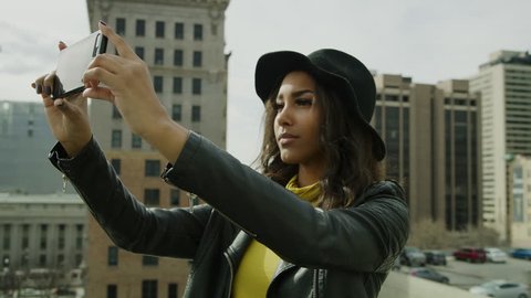 Woman taking panoramic photograph of city with cell phone on roof / Salt Lake City, Utah, United States