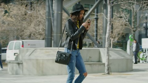 Slow motion shot of distracted woman texting on cell phone walking into post on sidewalk / Salt Lake City, Utah, United States