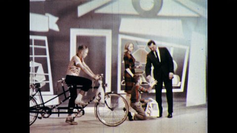 1960s: Boy gets on back of bicycle with other boy, boys ride to lemonade stand. Man and woman buy lemonade from girl. Girl puts fake coins into purse, sets out sign. Kids ride bicycle to bank.