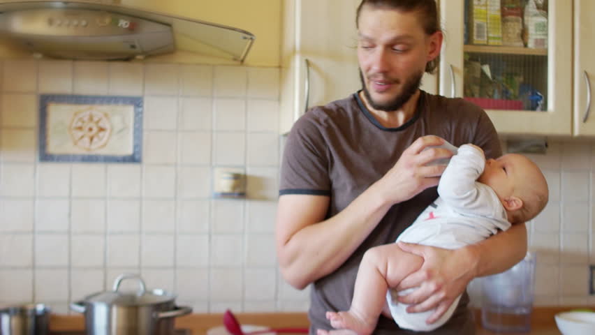 A man with an infant holds a soup on the stove. An effective father. When mom is not at home. Father's Day Royalty-Free Stock Footage #1014243779