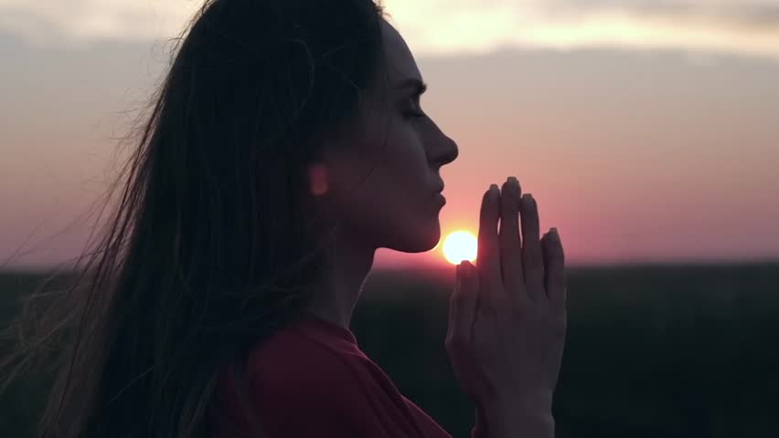 Silhouette of young woman praying with closed eyes in nature at sunset. Religion, spiritual and nature concept. | Shutterstock HD Video #1014247025