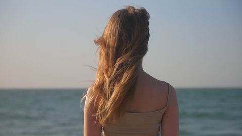 blonde woman is watching on a horizon of sea in sunny day, inspiring and thinking