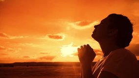 the girl prays. Girl folded her hands in prayer silhouette at sunset. lifestyle slow motion video. Girl folded her hands in prayer pray to God. girl praying asks forgiveness for sins of repentance