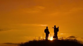 two men tourists hikers silhouette go to the mountains sunset travel slow motion video. Traveler successful young men walking on top of Mountain and waiting for sunrise. man travel tourists in the