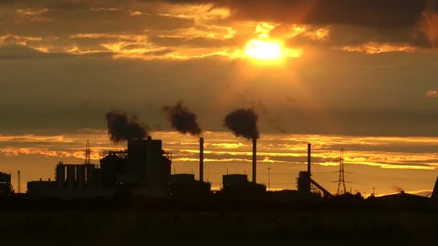 Petroleum oil refineries cooling towers with steam shot over corn wheat field and at sunset.  Filmed  in England, Yorkshire. 