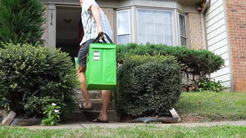 Fairfax, USA - September 12, 2017: Amazon Fresh insulated grocery delivery bags, totes on front home house porch closeup with young man picking them up, carrying inside home