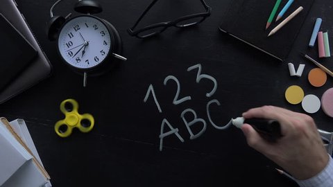 Teacher writing 123 ABC on school blackboard