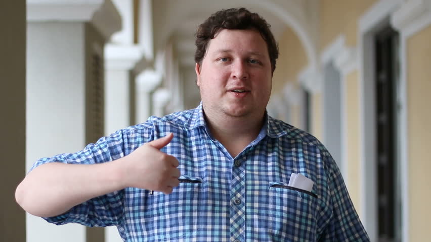 Portrait of a funny man giving thumbs up. Face of a fat man wearing plaid shirt outdoor.