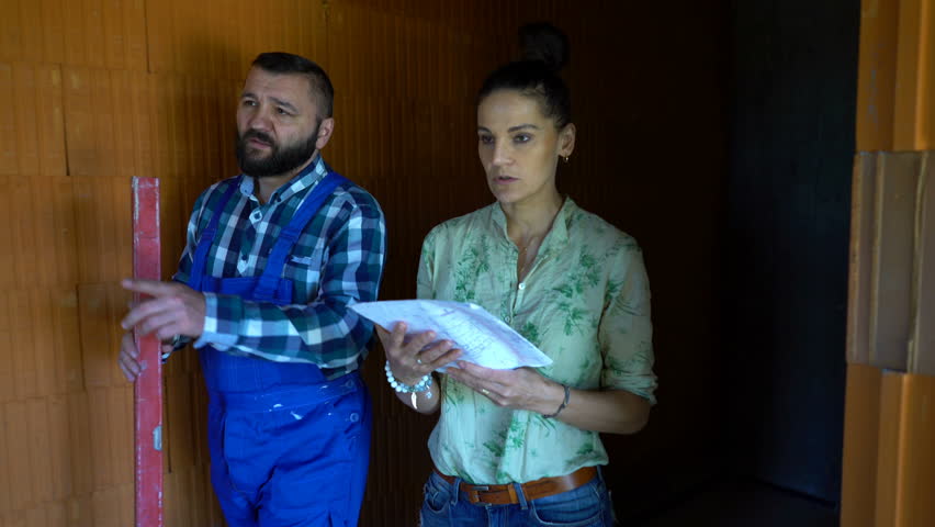 Young woman talking to construction worker at building site
