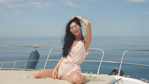 Young, attractive and rich caucasian businesswoman engages a yacht, having fotossesion on a luxury boat in sea at sunny summer day