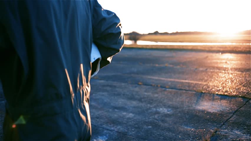 Unrecognizable Fighter Jet Pilot walking on the Air Base at Sunset.