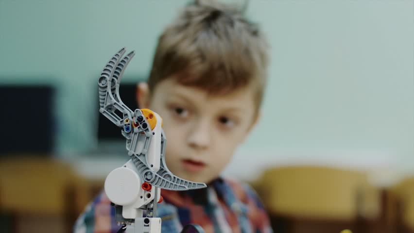 Close up shot of a lovely smart boy working on a new lego robotic claw in a club. Learning how to work with control panel. Programming robots. Royalty-Free Stock Footage #1014274913