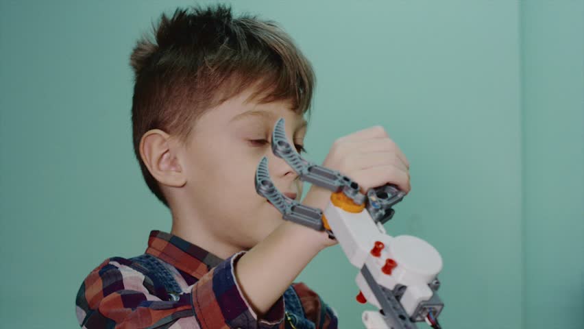 Close up shot of a little smart boy playing with lego robotic claw in robotics club. Happy boy fighting with robotic claw. Fun time. Royalty-Free Stock Footage #1014274916