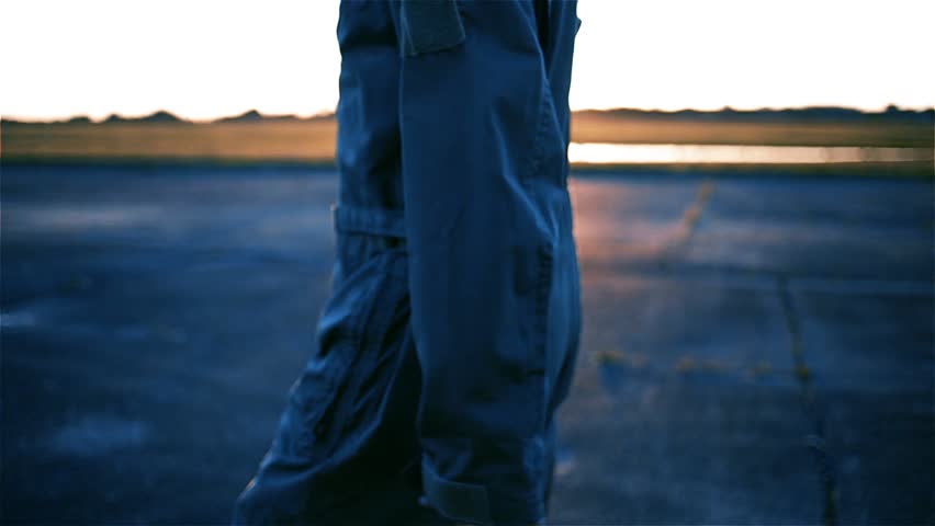 Jet Pilot walking on the Airfield at Dawn. Low Angle View.