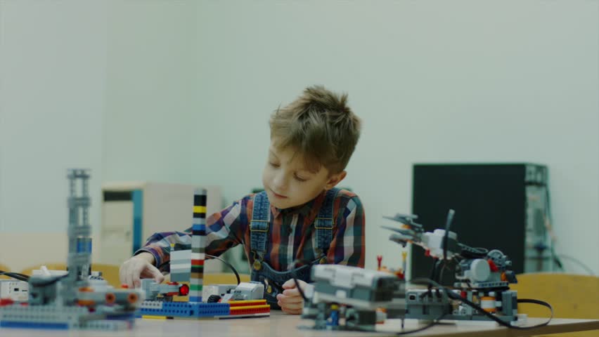Young talented boy is in the engineering club working with robots. Lego robots on the table. Modern technologies. Boy playing indoor. Royalty-Free Stock Footage #1014275204