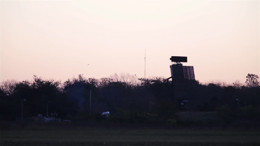 Airport Radar Tower and Flock of Birds at Sunset.