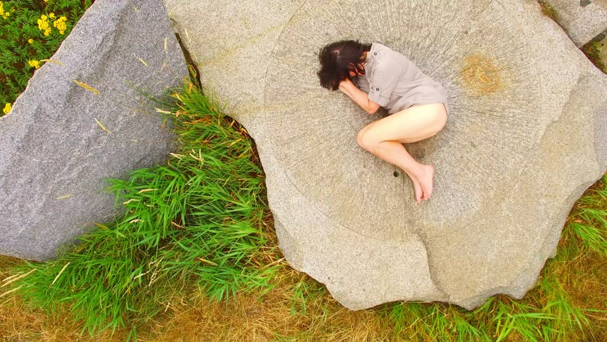 Young woman during tantric ritual lying under a menhir.  Famous place near Tesovice for every year rituals of fertility treatment. Mysterious landmark in Czech Republic, Central Europe.
