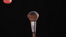 Concept of cosmetics and beauty. Make-up brushes with pink powder explosion on black background