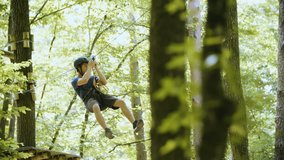 Person slide down the zip-line in slow motion 4K. Long shot rack focus tracking of a climber in focus sliding on a wire while wearing safety equipment and helmet. Climbing experience in adventure park - Powered by Shutterstock - Get 15% off with code: PIKWIZARD15