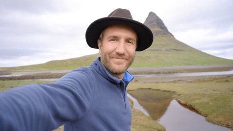 Young man travelling in Iceland on a road trip takes a selfie in nature. Male solo traveller surrounded by nature in Iceland taking selfies. Travel and lifestyle concept 