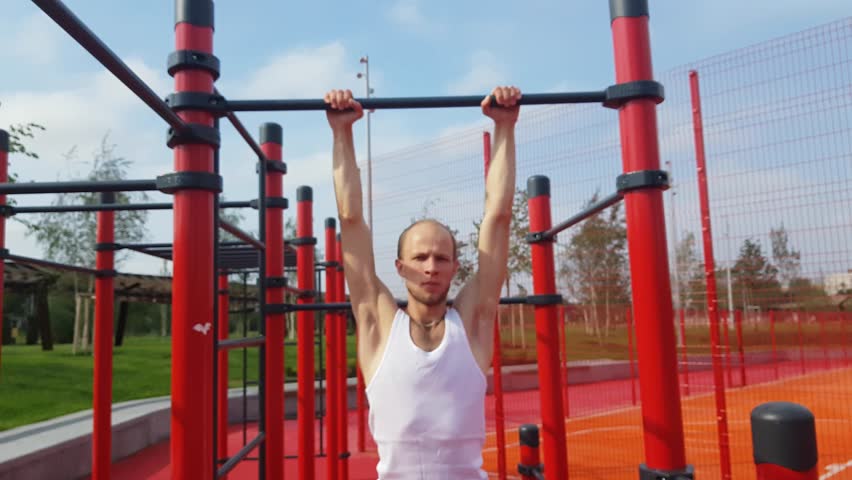 Man makes exercises on a turnstile outdoors