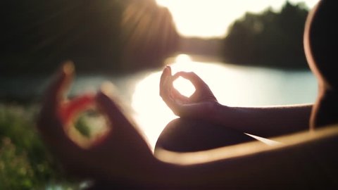 Young healthy girl practicing yoga by the lake at summer evening, shallow dof, close up on girls hand, fitness health nature energy concept, shot in 4K UHD Arkistovideo