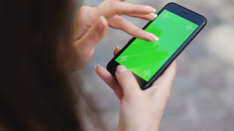 Lviv, Ukraine - May 5, 2018: woman hands using iPhone smartphone with touch green screen browsing social network closeup view swapping tapping scrolling zooming chroma key display mock-up