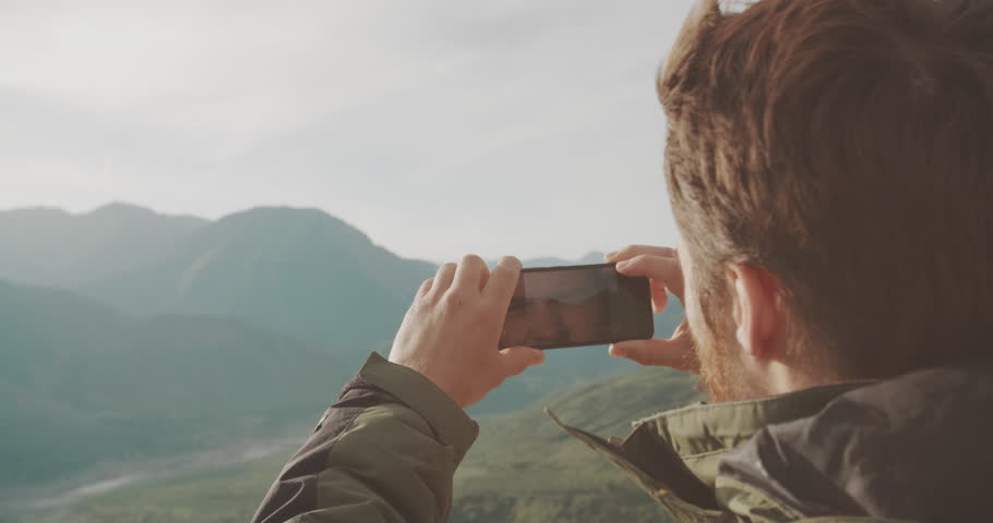 Young adventurer taking picture of mountains. climber on top of mountain. social networks concept 4k