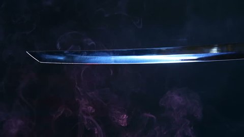 Japanese katana sword. Blade close-up on a dark background with blue light filter with incense smoke. Steel tempering