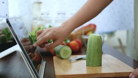 4K. female hand slicing cucumber, prepare ingredients for cooking follow cooking online video clip on website via tablet. cooking content on internet technology for modern lifestyle concept