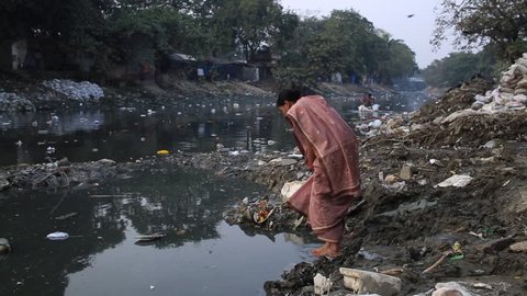 Kolkata, India, January 2016. A woman prays in a heavily polluted river in a slum of Kalighat.