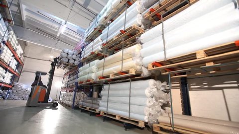 A large warehouse of textile products and goods, in the warehouse operates elektroropogruzchik. Warehouse stylings. Sewing or furniture production.