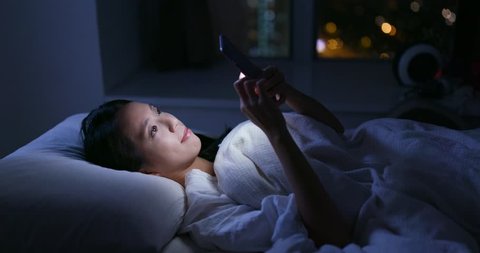 Woman use of mobile phone and lying on bed at night