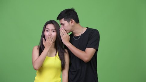 Young Asian couple whispering to each other