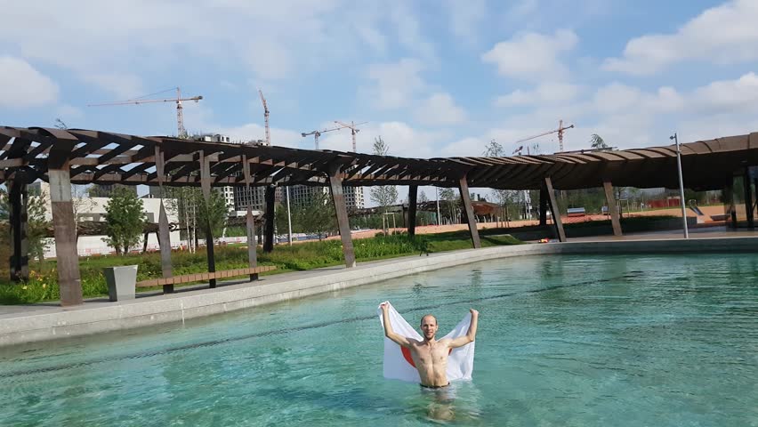 Happy man with flag of Japan in pool.