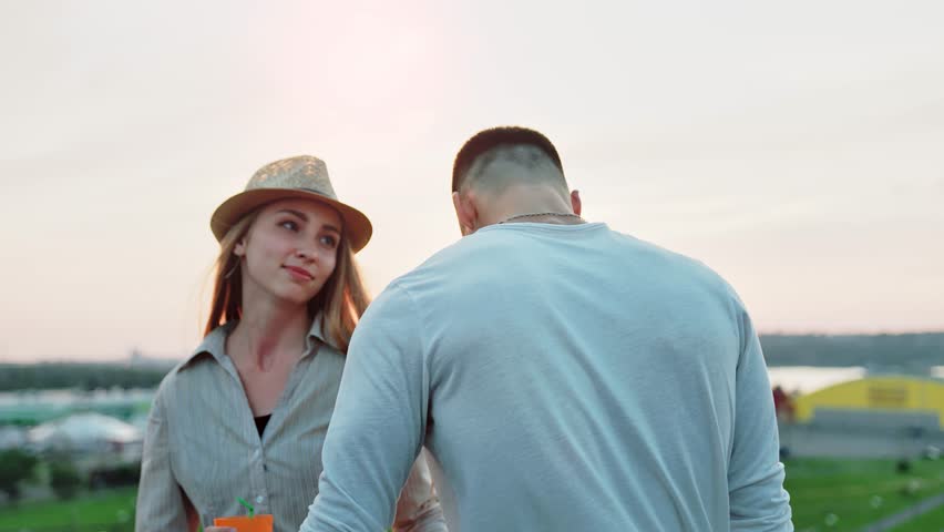 Two young students people dancing and enjoying sunset at summer rooftop party