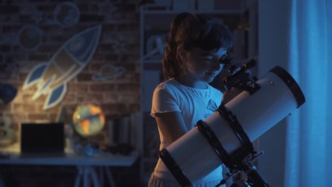 Happy young girls stargazing with a telescope, they are learning astronomy together at home