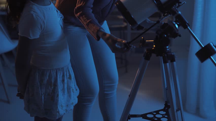 Sisters stargazing together and learning astronomy, the older girl is setting the telescope
