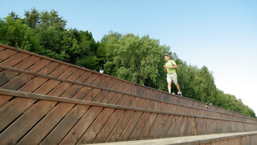 Mature man fitness is engaged in the bek in the open air, in headphones. Super slow motion fhd