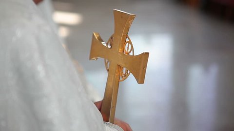 The priest in the church holds a cross in hands and gives a farewell to a young couple