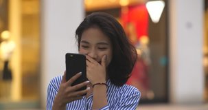 One pretty young asian woman video chatting with friend on mobile phone in the street at evening, 4k.