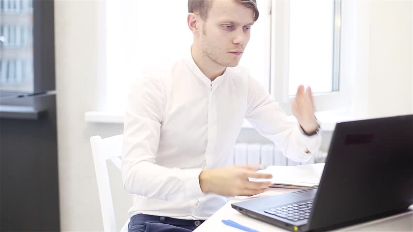 Dispute by video link laptop in the office. Young businessman angrily yells into the screen. Royalty-Free Stock Footage #1014383639