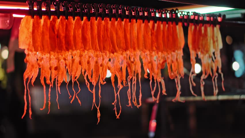 traditional street Asian food, a night food market, squid hanging in a shop